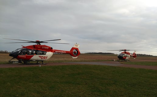 Zwei Hubschrauber der DRF Luftrettung des Typs H145 mit Fünfblattrotor stehen auf einem Flugplatzvorfeld