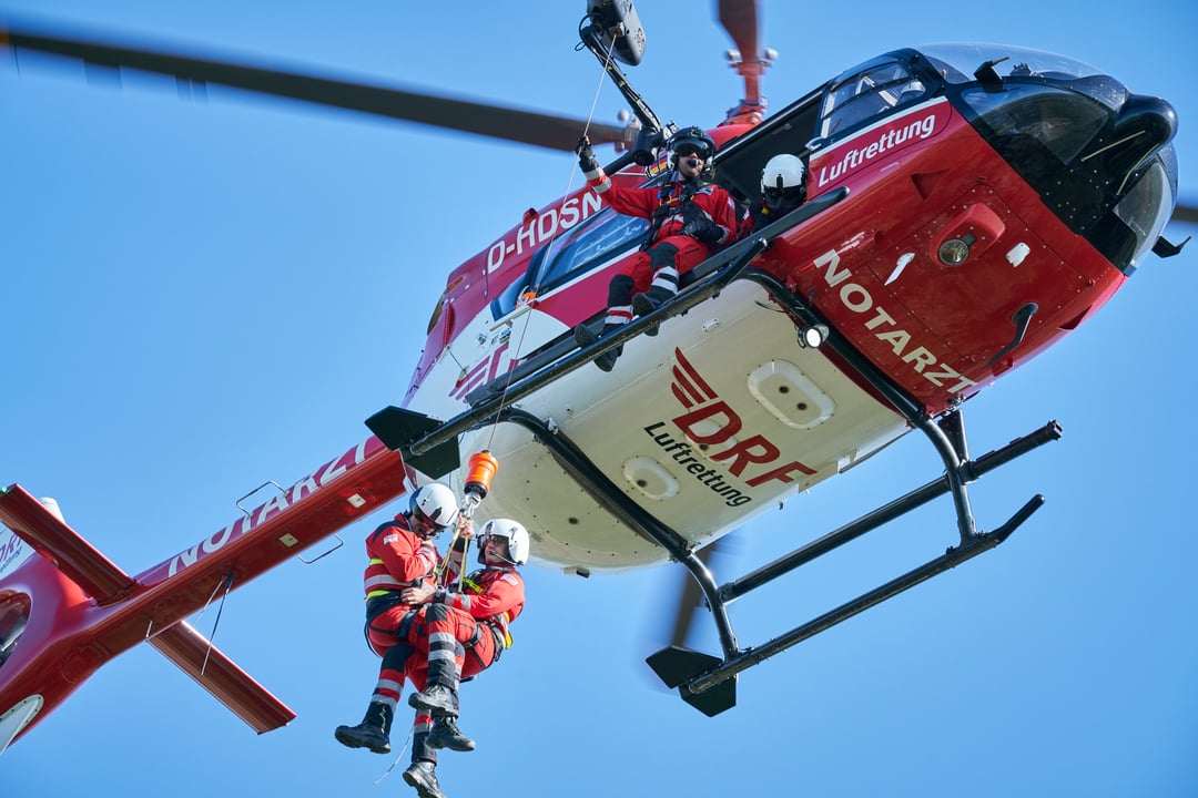 Zwei Personen werden an einer Rettungswinde am Hubschrauber herunter gewincht.